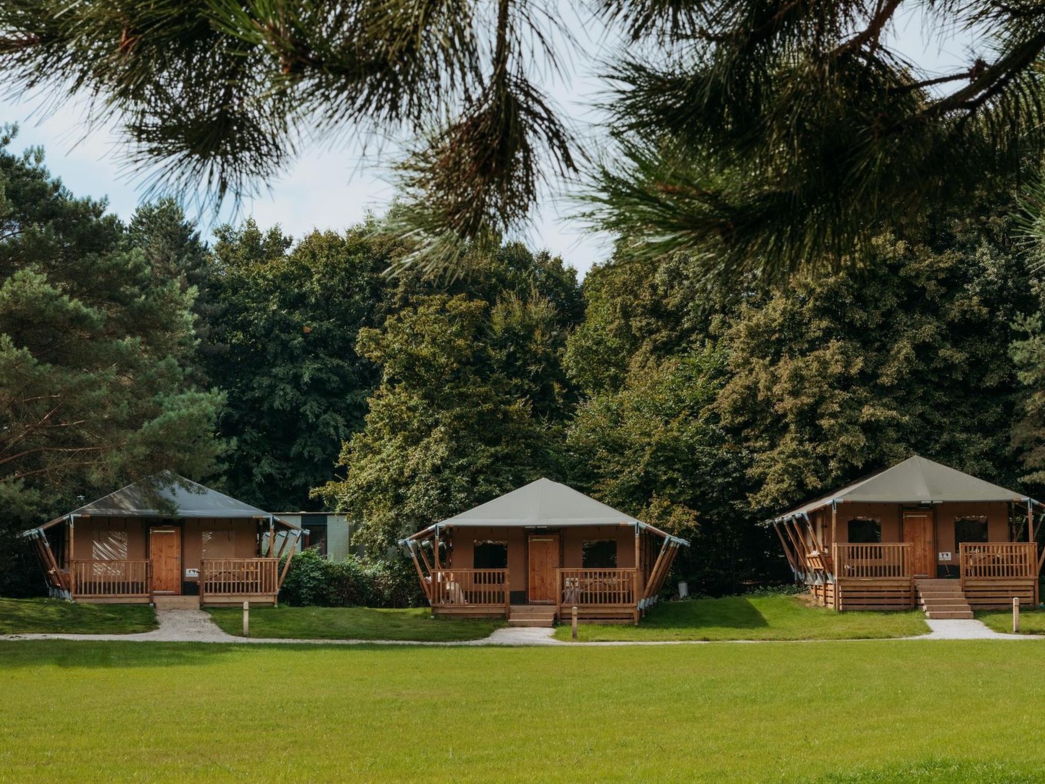 "De Glamping - Trio Lodge | 18p", chalet 6-kamers 125 m2. Het objekt is geschikt voor 18 volwassenen. 1 kamer met 2 x 2 stapelbedden. 1 kamer met 1 2-pers bed. 1 kamer met 2 x 2 stapelbedden. 1 kamer ..